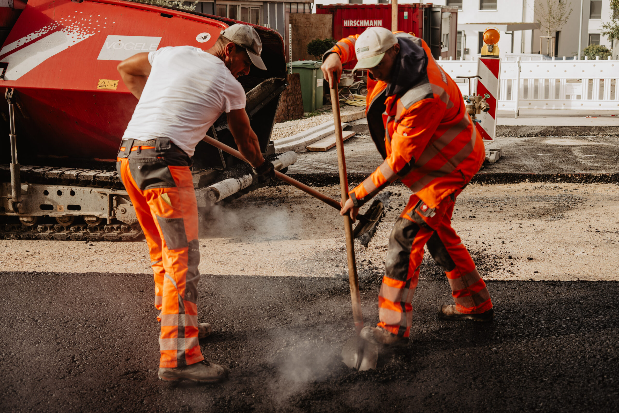 Mitarbeiter der Asphaltkolonne beim Asphalteinbau Asphaltfertiger der Hans Hirschmann KG Walze beim Straßenbau Team der Asphaltkolonne auf der Baustelle